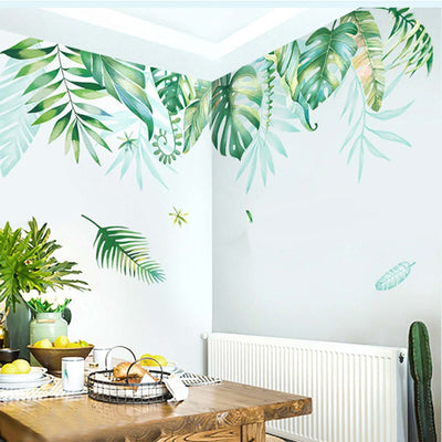 Decorative green leaf wall decals in a bright dining area with a wooden table.