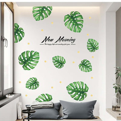 Wall art featuring green monstera leaves and the text "New Morning" in a modern interior.