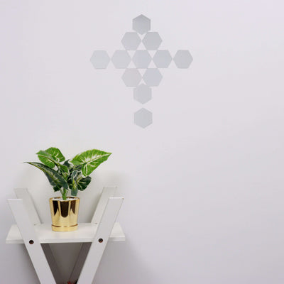 Decorative hexagon wall art above a potted plant on a white side table.