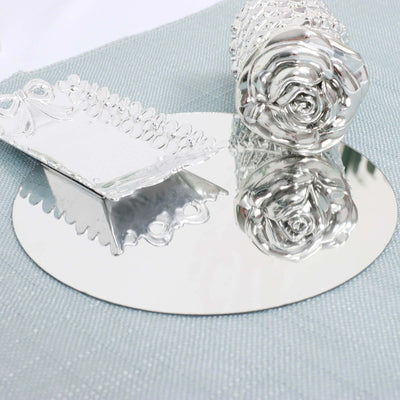 Silver decorative items including a rose and a dish on a reflective surface.