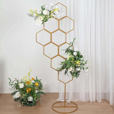 Gold hexagonal flower stand with artificial flowers and greenery.