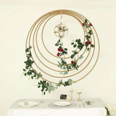 Gold circular hanging decor with greenery and roses, perfect for events or home decor.