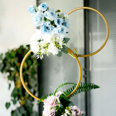 Floral arrangement with blue and white roses in decorative gold hoops.