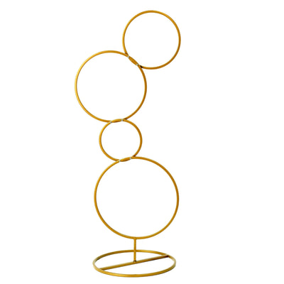 Gold circular sculpture with a modern design on a plain background.