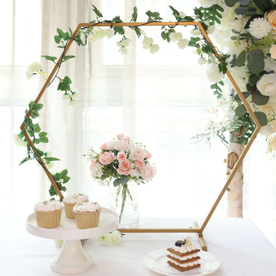 Decorative hexagonal floral arch with cupcakes and a bouquet of roses.