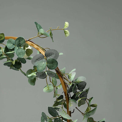 Artificial greenery arch with lush leaves and a curved frame.