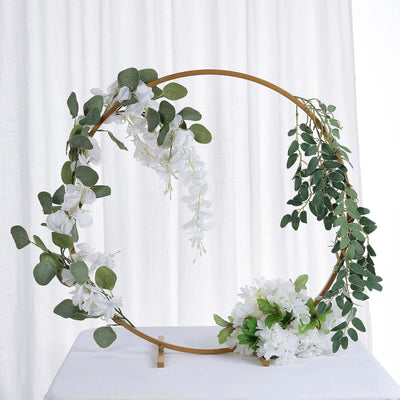 Floral hoop decoration with white flowers and green leaves on a stand