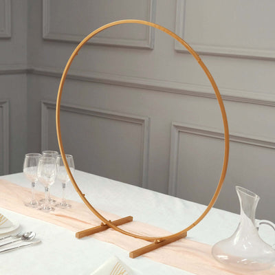 Gold circular display stand on a table with glassware and a pitcher.