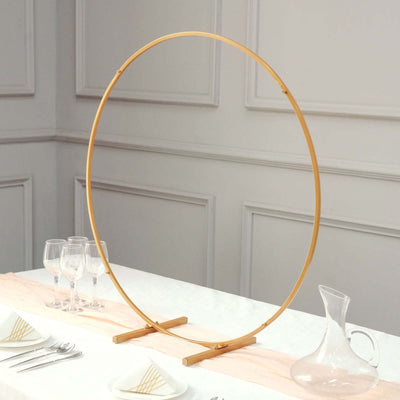 Gold circular display stand on a table setting with glassware and a pitcher.