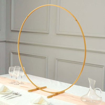 Gold circular photo backdrop stand on a table with glassware and a pitcher.