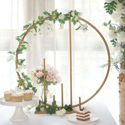 Gold floral display stand with cupcakes and flowers in a bright setting.