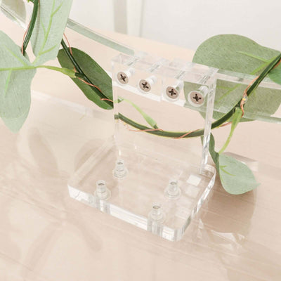Acrylic display stand with screws, surrounded by greenery.