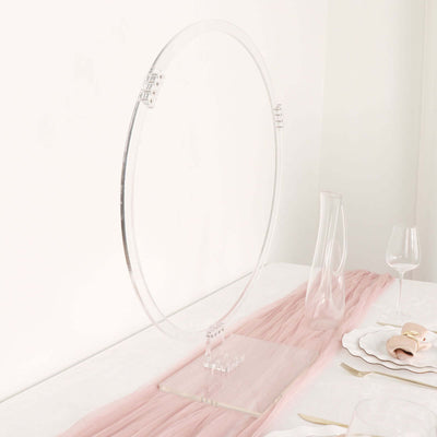 Acrylic circular display stand on a table with pink fabric.