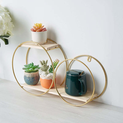 Gold circular shelf with potted plants and a mug on a light wooden surface.