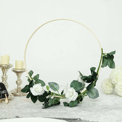 Floral hoop decor with white roses and greenery on a neutral background