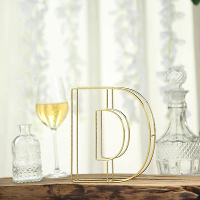 Gold wire letter "D" decorative piece on a wooden table.