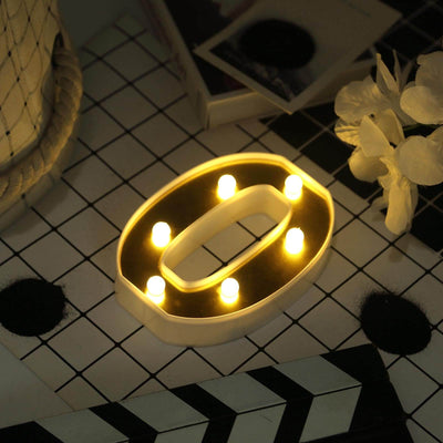 Decorative light-up number "0" with warm glow on a patterned surface.