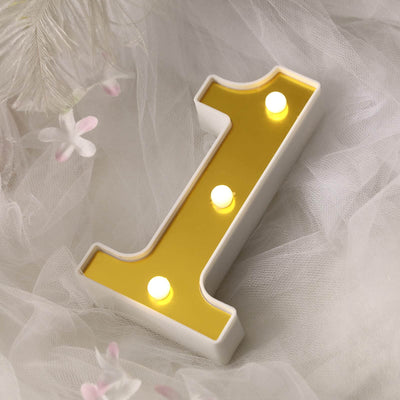 Gold number one decorative light with three bulbs on a soft white backdrop.
