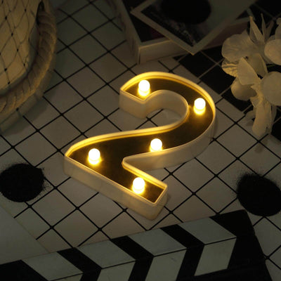 Illuminated marquee number two with warm lights on a patterned surface.