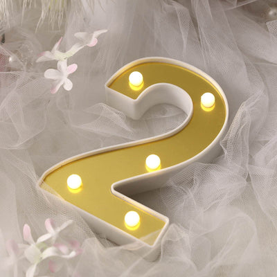 Yellow illuminated number two decor with lights on a soft fabric background.