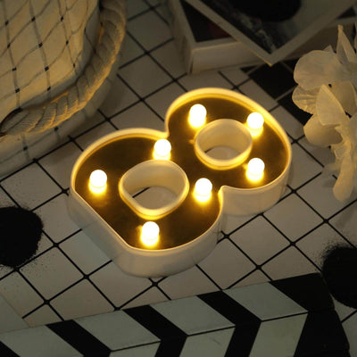 Decorative LED number 88 candle with warm glow on a patterned surface.