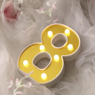 Yellow number 8 light with bulbs, styled on soft tulle fabric.