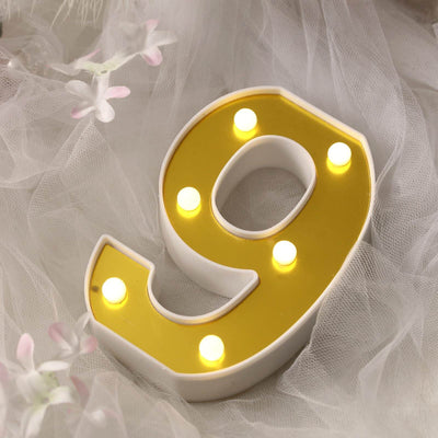Yellow light-up number 9 decoration on soft white fabric.
