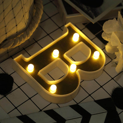 Light-up decorative letter "B" with warm glowing bulbs on a patterned surface.