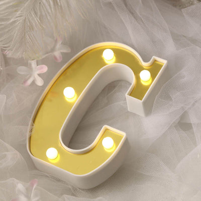 Decorative letter "C" marquee light with warm yellow bulbs.