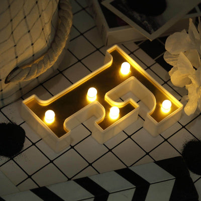 Decorative letter 'H' with LED lights on a stylish tabletop setting.
