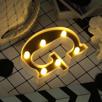 Illuminated letter "G" marquee light on a patterned surface.
