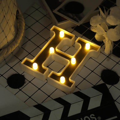 Illuminated letter "H" marquee sign on a stylish background.