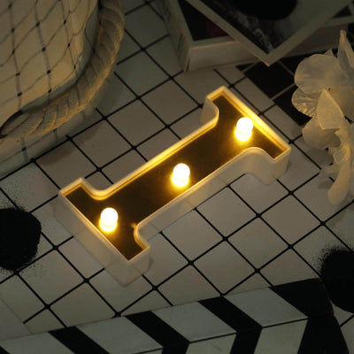 Decorative LED light in a modern letter 'H' design on a patterned table.
