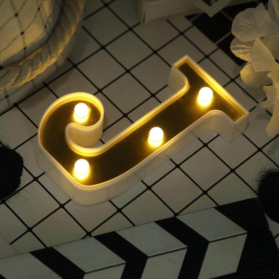 Decorative letter "J" with lights on a patterned surface.