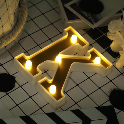 Marquee letter "K" with LED lights on a patterned surface.