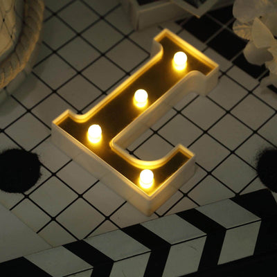 Illuminated letter "L" marquee light on a patterned surface.