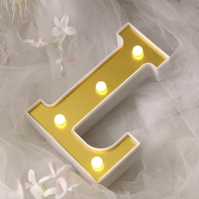 Yellow LED letter "L" light decor on soft white fabric background.