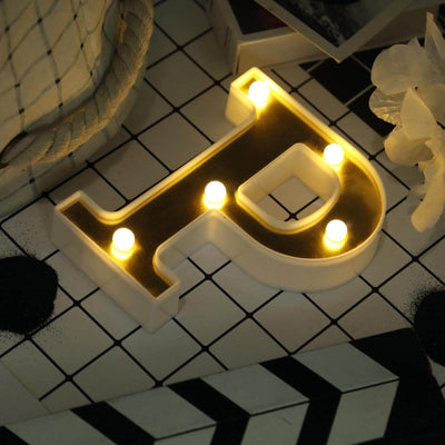 Decorative letter "P" light with warm bulbs on a styled tabletop.