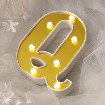 Yellow marquee letter "Q" with LED lights on a soft background.