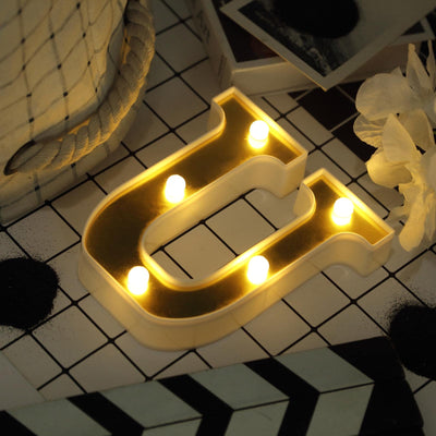 Light-up letter "U" decor with warm bulbs on a stylish surface.