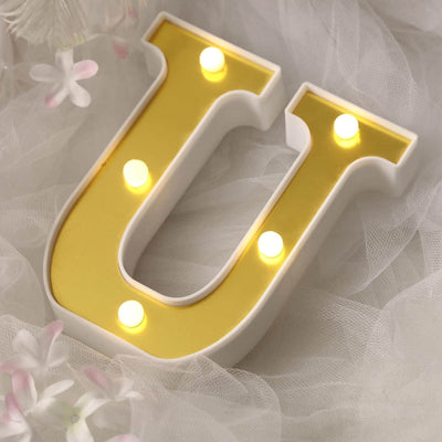 Decorative letter "U" with lights on soft fabric backdrop.