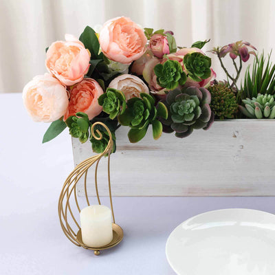 Decorative floral arrangement with succulents and a gold candle holder on a table.