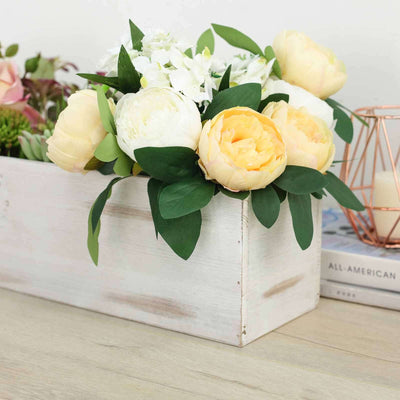 Floral arrangement in a rustic wooden box with greenery.