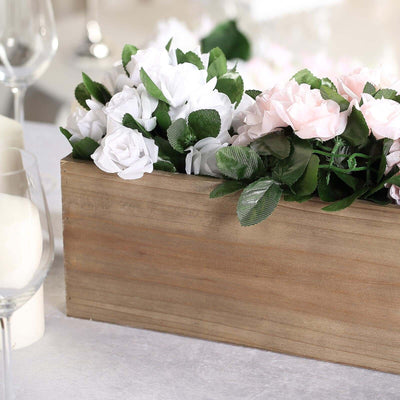 Wooden box with artificial white and pink flowers arranged decoratively.