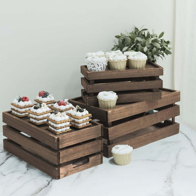 Wooden dessert crates with cupcakes and cookies on a marble surface.