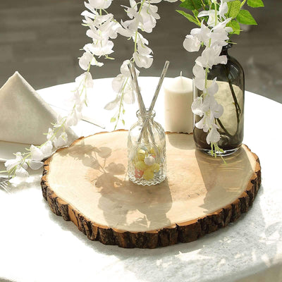 Decorative wooden slice with a glass diffuser and floral arrangement on a table.