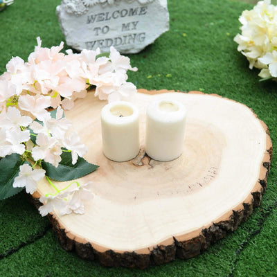 White candles on a wooden slice with flowers and a welcome sign for a wedding.
