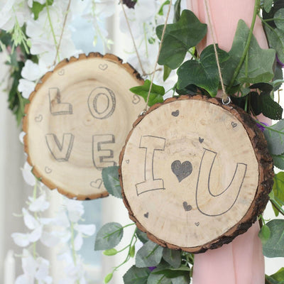 Wooden love signs with heart designs hanging among greenery and flowers.
