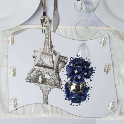 Eiffel Tower replica on a mirrored plate with decorative flowers and pearls.