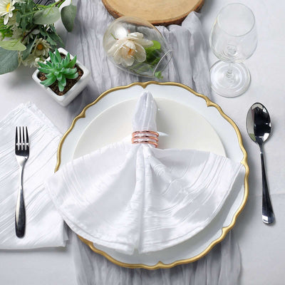 Elegant dining table setting with white napkin, gold plate, and glassware.